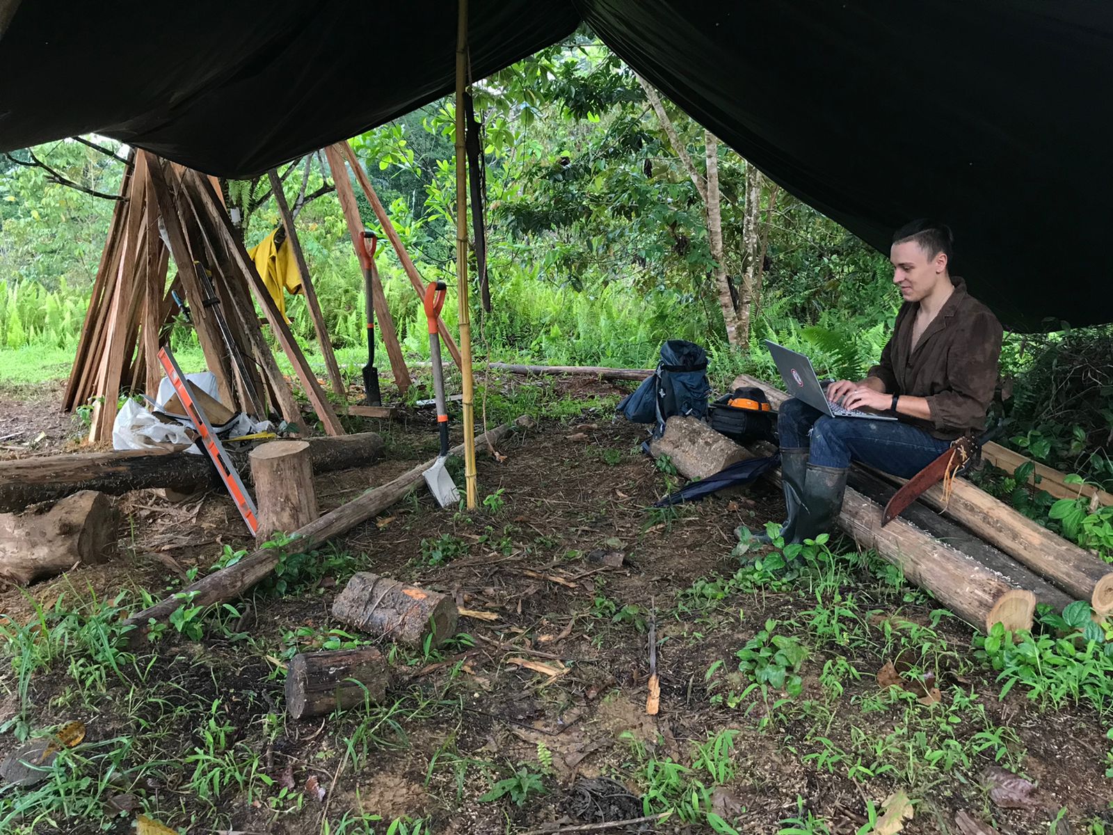 Junger Mann der im Dschungel sitzend an einem Sprachkurs teilnimmt
